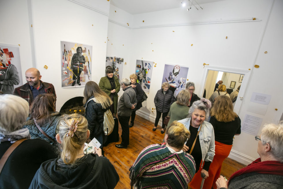 A crowd of people is standing in an exhibition room.