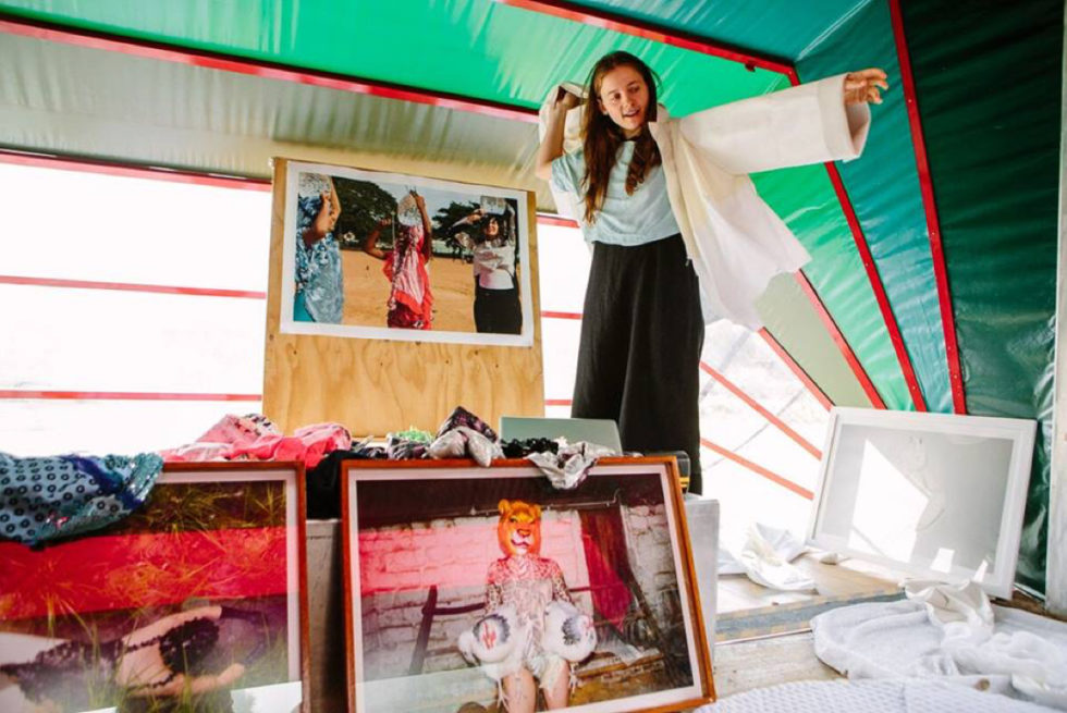 A person putting a jacket on inside Nebula, our portable arts space.