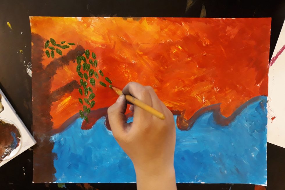 A hand is paining a landscape.