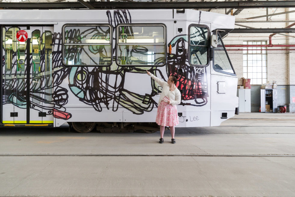 Jocelyn Lee in front of an Art Tram with her work on it.