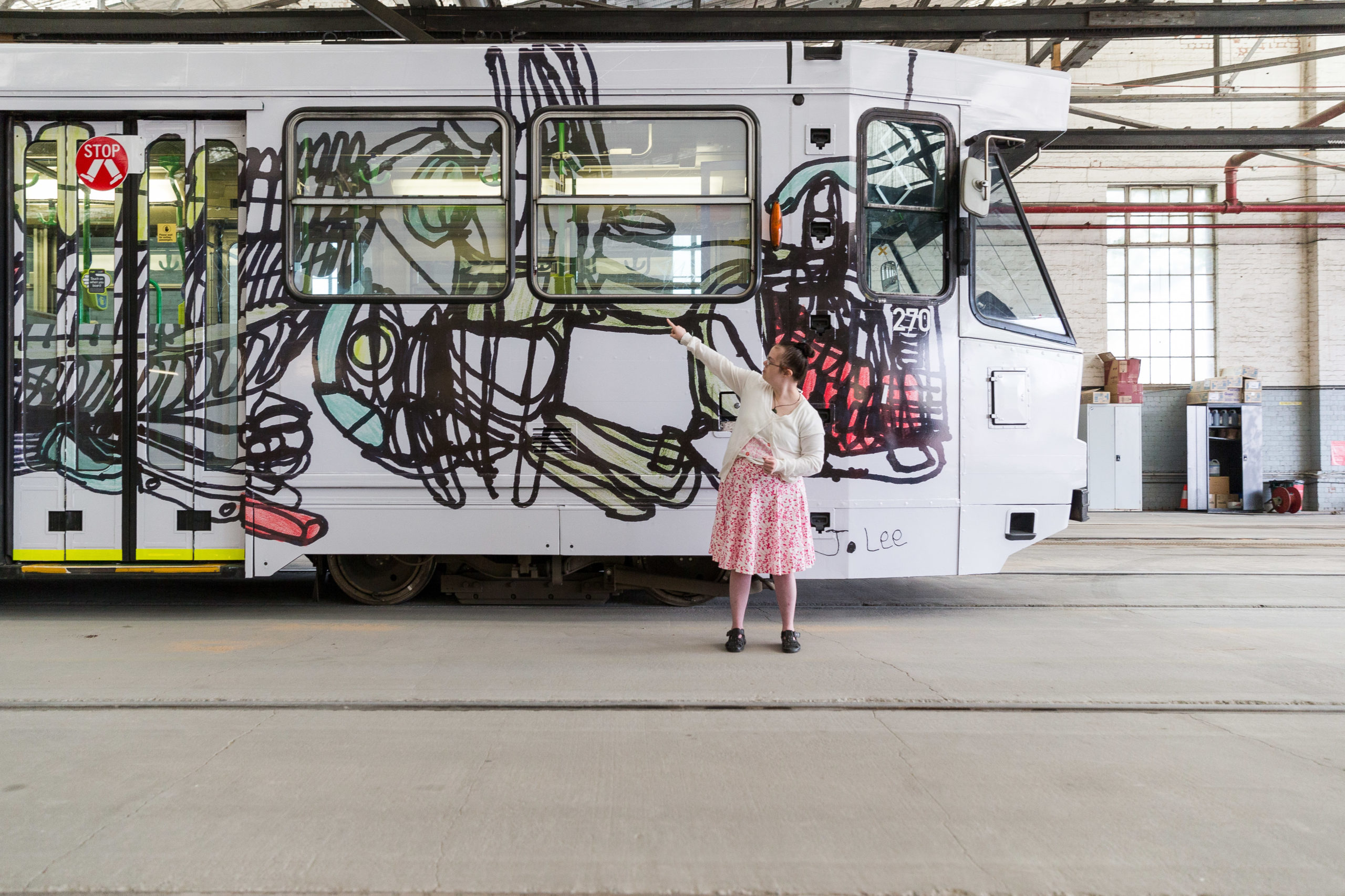 Jocelyn Lee in front of an Art Tram with her work on it.