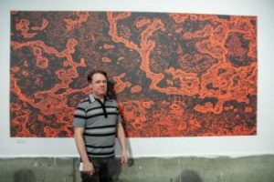 Jonathon standing in front of his artwork