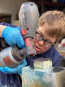 Robert using a silicone gun on a wooden sculpture.