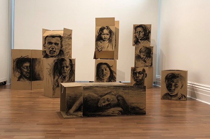 Cardboard boxes with drawings of people's faces on them.