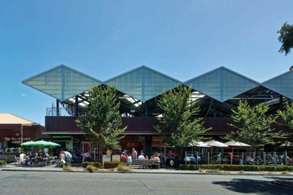 the side view of south melborune market with people sitting around in front.