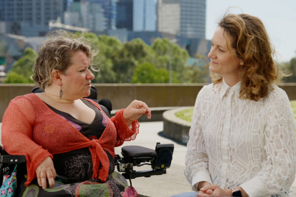 Caroline Bowditch and Claire Spencer in conversation outside on a sunny day.