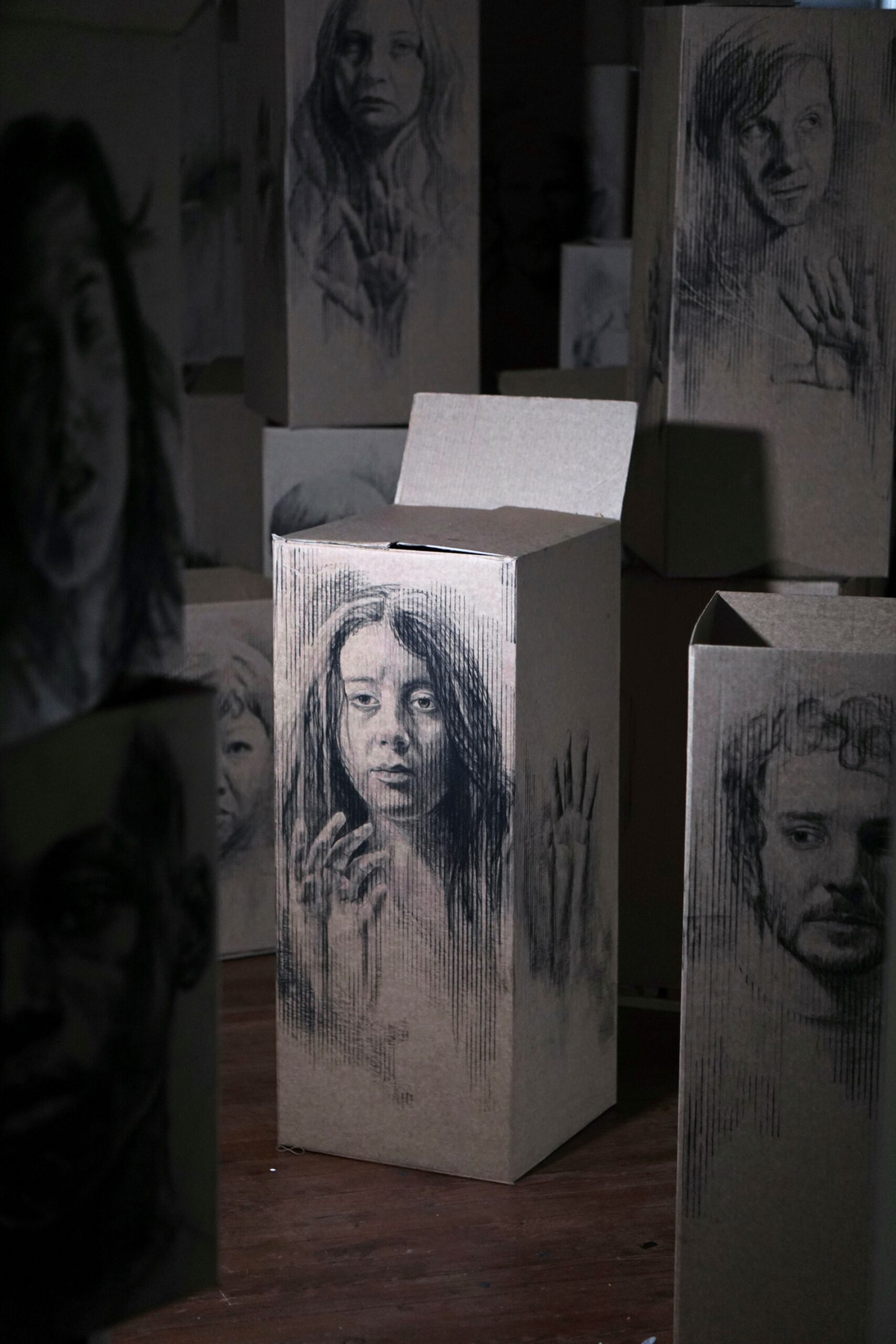 A charcoal drawing of a young woman on a cardboard box