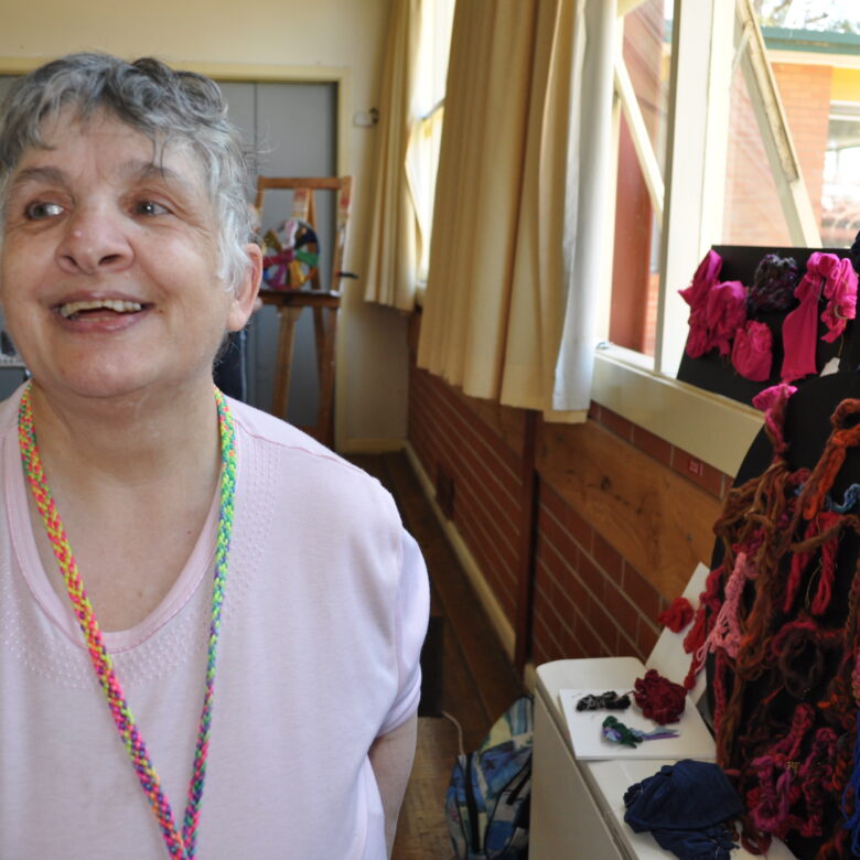 Lorraine smiling next to a black and red textile artwork.