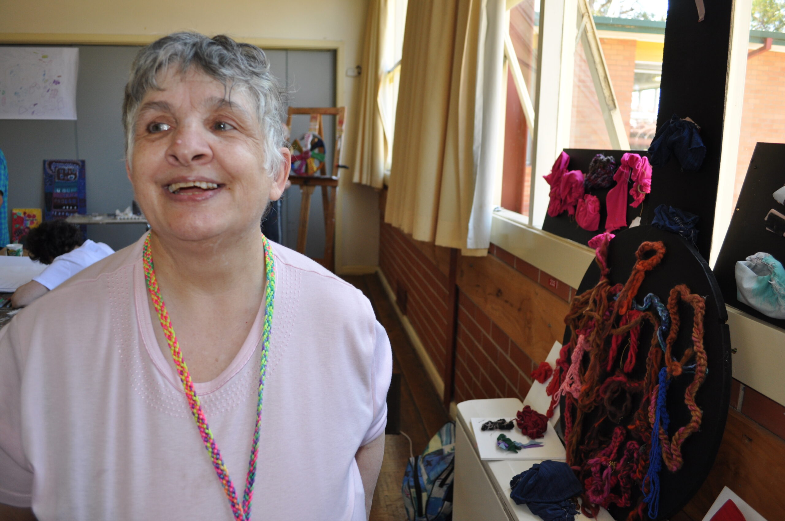 Lorraine smiling next to a black and red textile artwork.