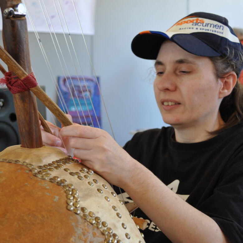 Paula seated holding a large string instrument.