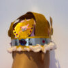 mannequin's head facing a wall wearing a royal crown made of gold paper and sequins and fluffy cotton wool trimmings.
