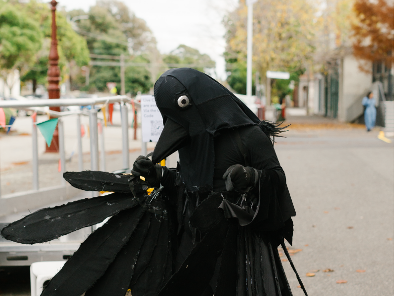 a person in a crow costume is walking.