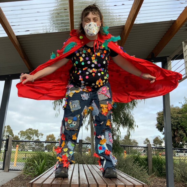 Heather White in a red cape wearing a face mask in a bird costume.