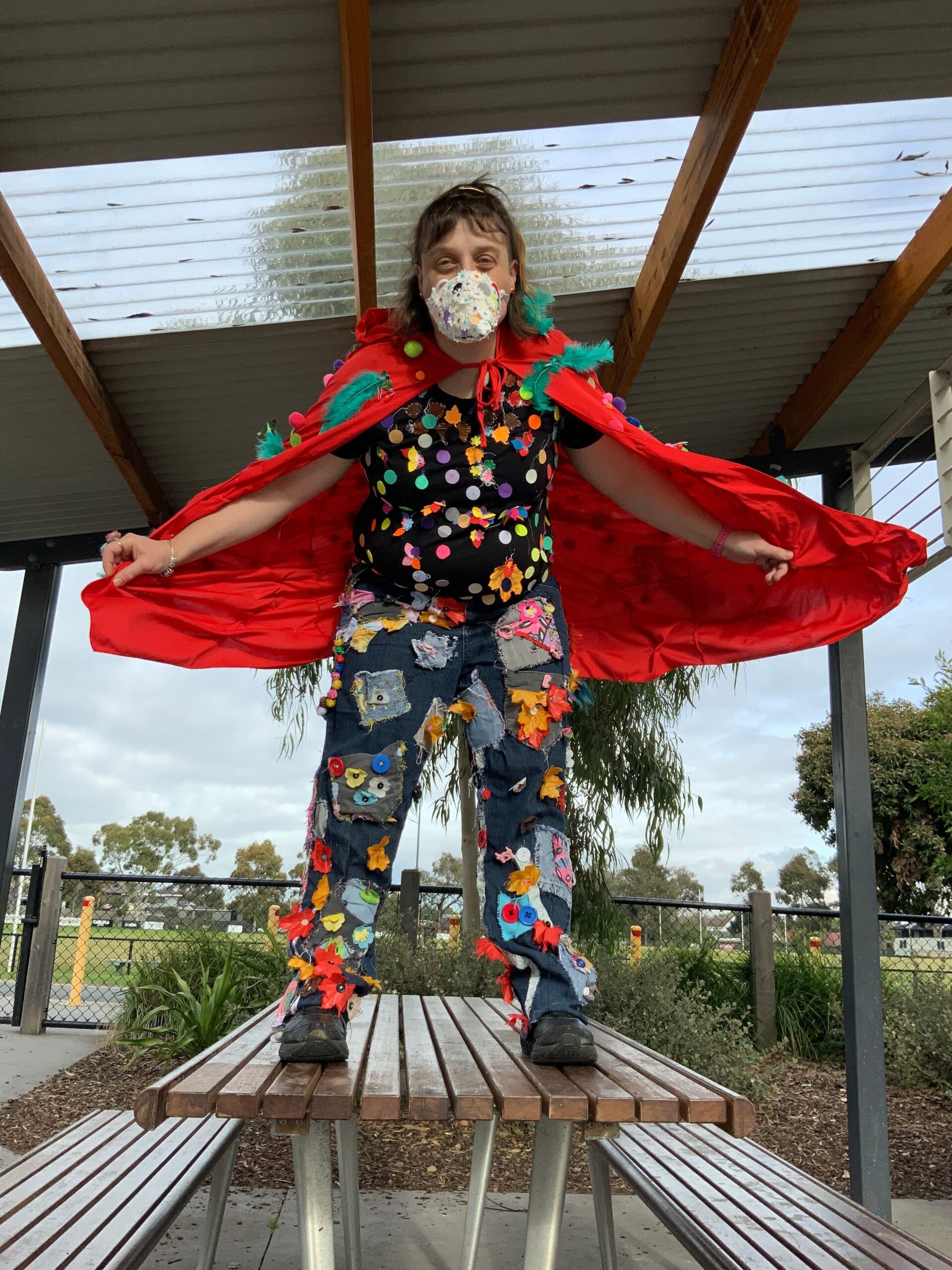 Heather White in a red cape wearing a face mask in a bird costume.