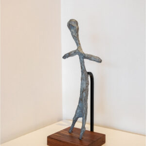 grey and silver textured figure standing on a natural wood base.