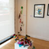 installation view of colourful textile sculpture on a plinth that is cascading off the plinth and on the gallery floor and creeping up a wall.