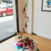 installation view of colourful textile sculpture on a plinth that is cascading off the plinth and on the gallery floor and creeping up a wall.