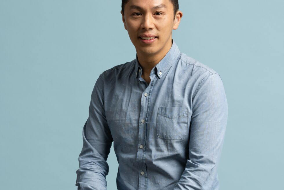 Elvin Lam seated in a blue shirt.