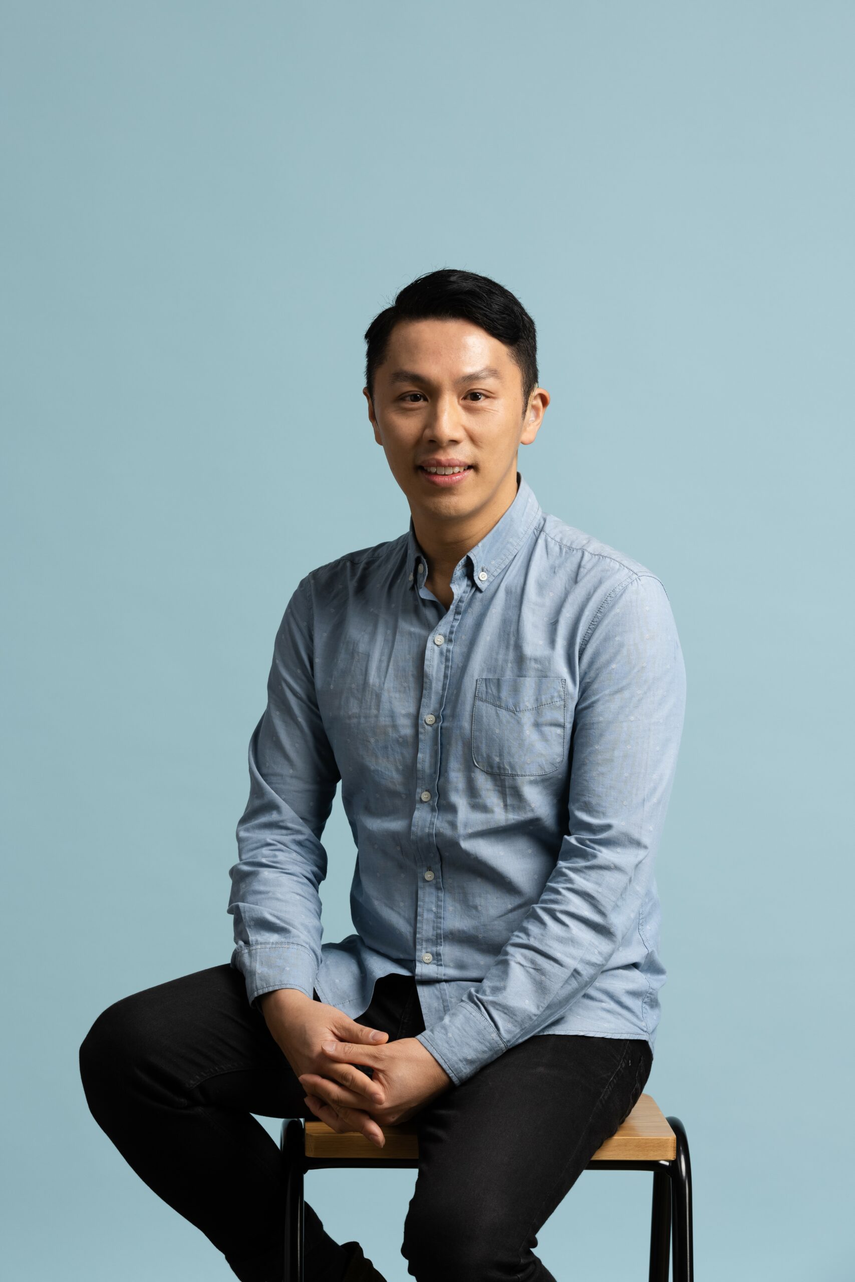 Elvin Lam seated in a blue shirt.