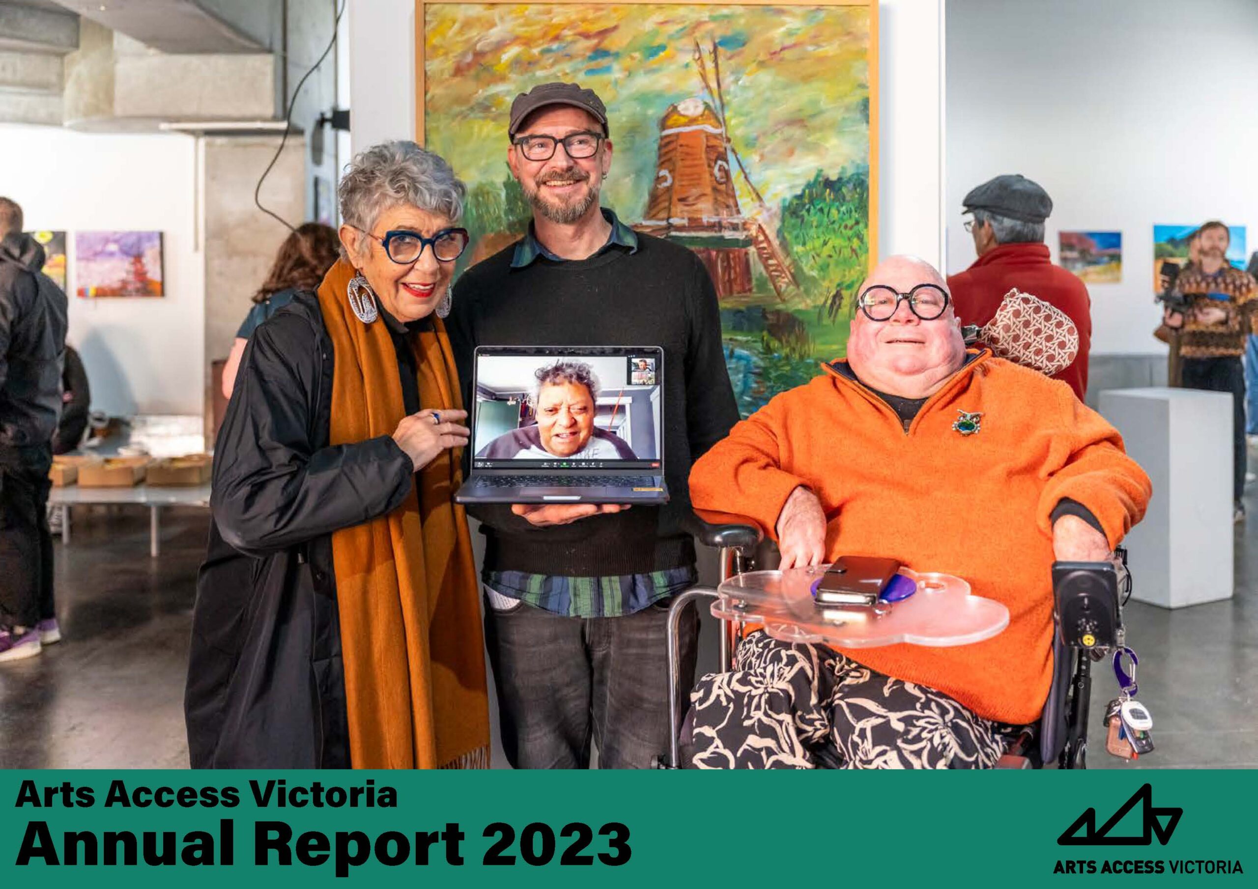 Three people in an art gallery, Aunty N’arweet Carolyn Briggs AM, PJ Noack in front of a lansdscape painting featuring a windmill. Uncle Greg Muir is seen on a laptop held by PJ Noack.