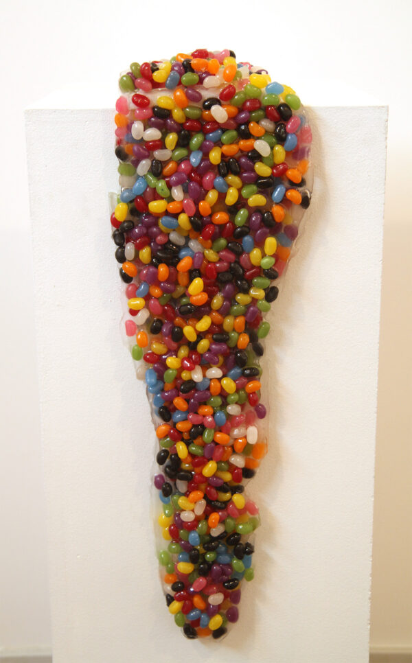 A dripping mass of jelly beans drips down a white background.