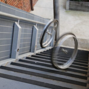 Two wheels are seen in motion rolling down a set of stairs.