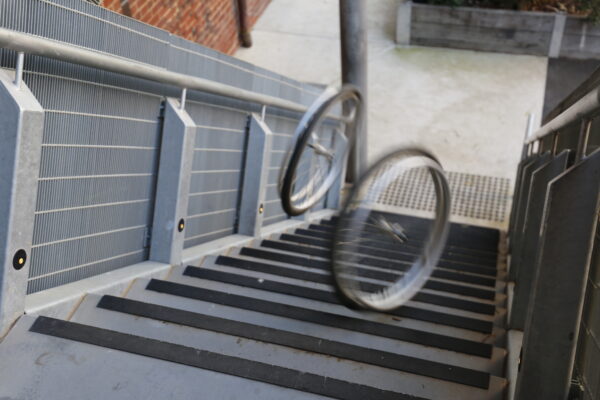 Two wheels are seen in motion rolling down a set of stairs.