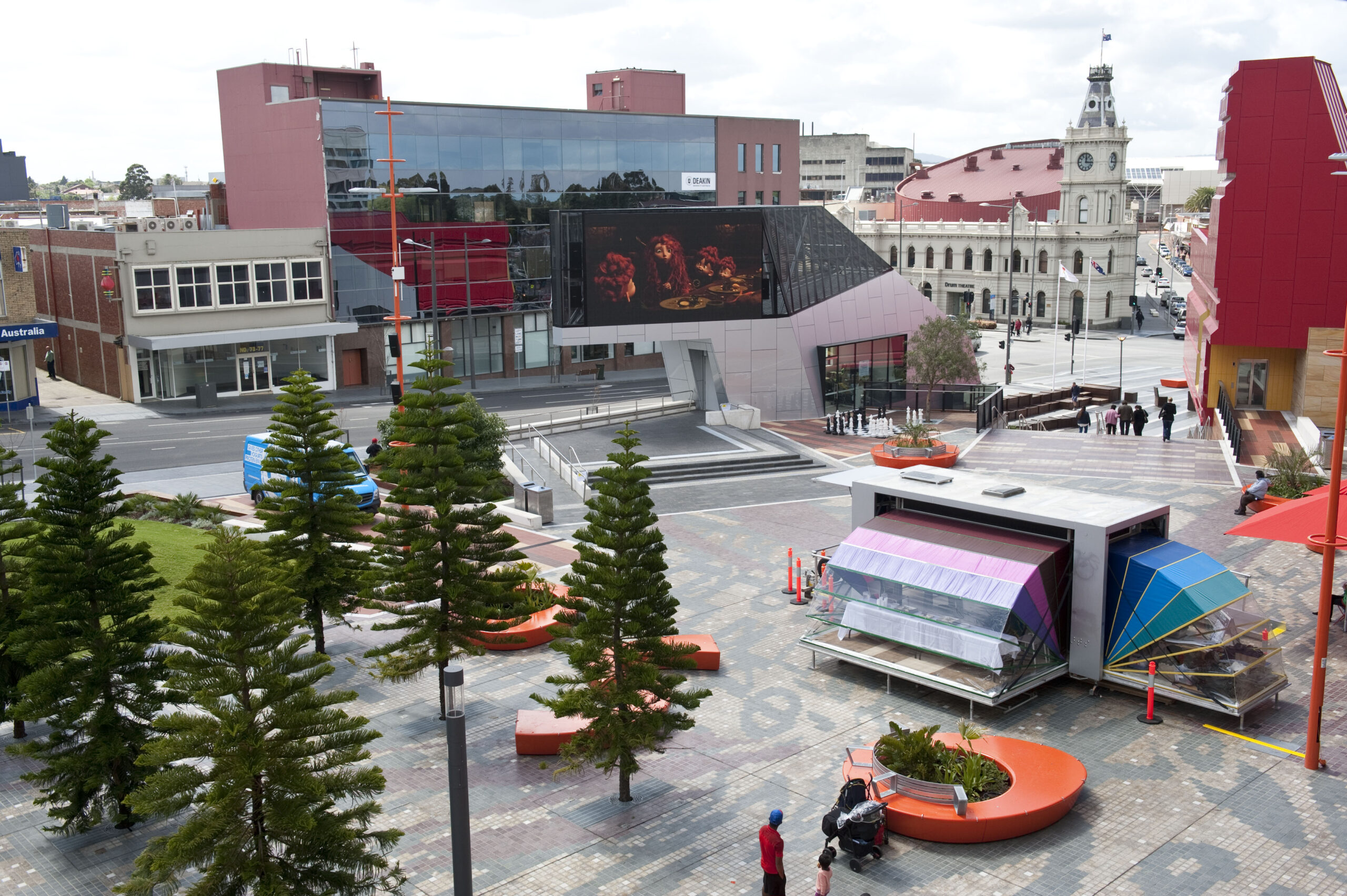 Nebula art space in a city square with tall fir trees to the side