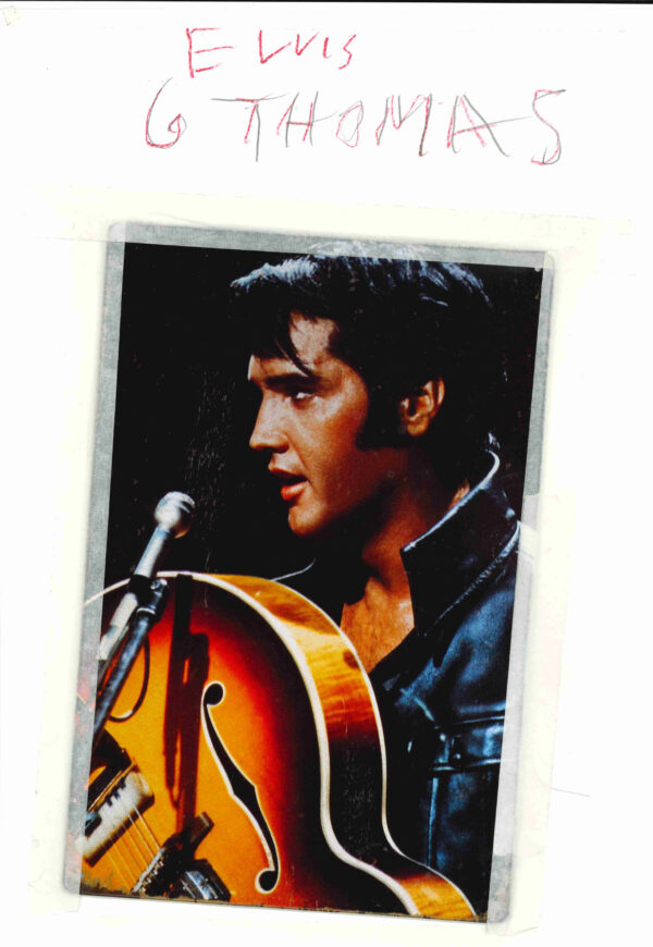 A photograph of Elvis holding a guitar attached to a piece of paper using making tape. With the name Elvis. G. Thomas written on top using red pencil colours.