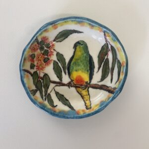 A small bowl featuring a parrot perched on a branch.
