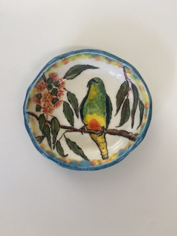 A small bowl featuring a parrot perched on a branch.