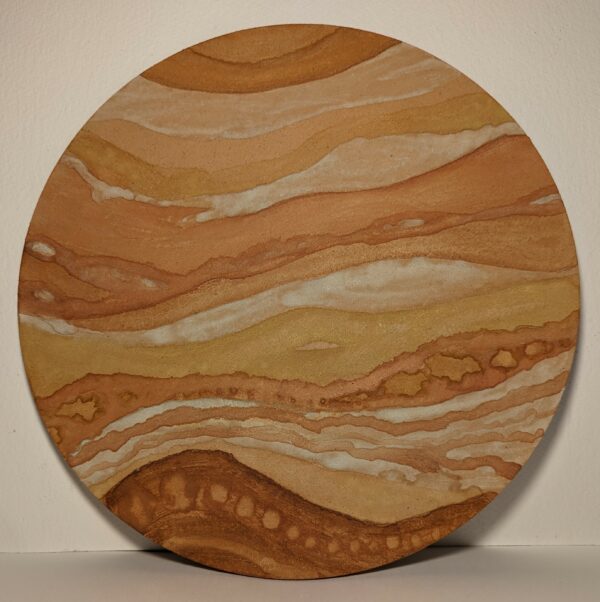 An ochre painting on a round wooden board featuring repetitive curved lines and circular patterns in earthy tones giving the impression of a landscape.