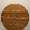 An ochre painting in earthy tones on round wooden board with bumpy lines at irregular spaces going horizontal across the board.