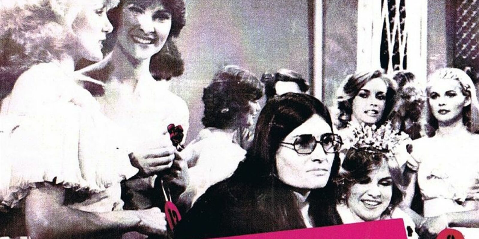 Lesley Hall on stage at Beauty Quest 1981 surrounded by contestants holding a protest sign