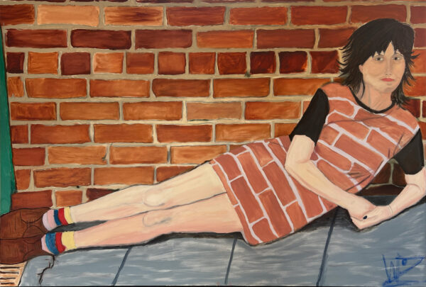 A figure lays in front of a red brick wall looking directly at the camera wearing a dress that also has a red brick pattern on it.