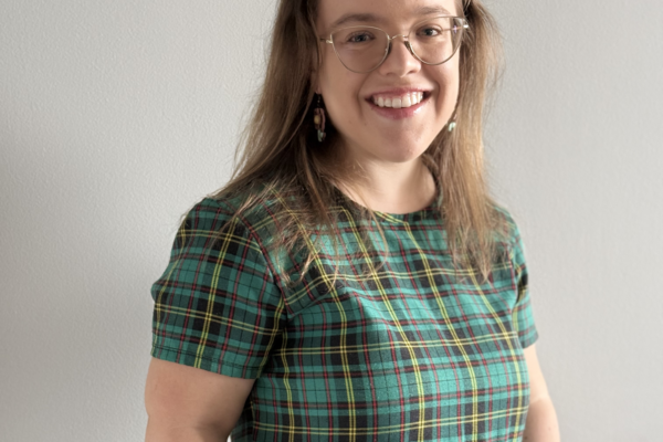 A person of short stature with glasses wearing a plaid green dress.