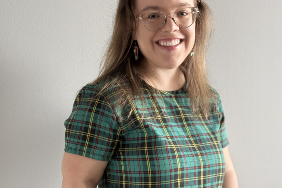 A person of short stature with glasses wearing a plaid green dress.