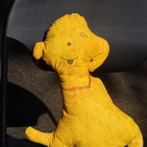 A soft sculpture of an animalistic friendly yellow dog.