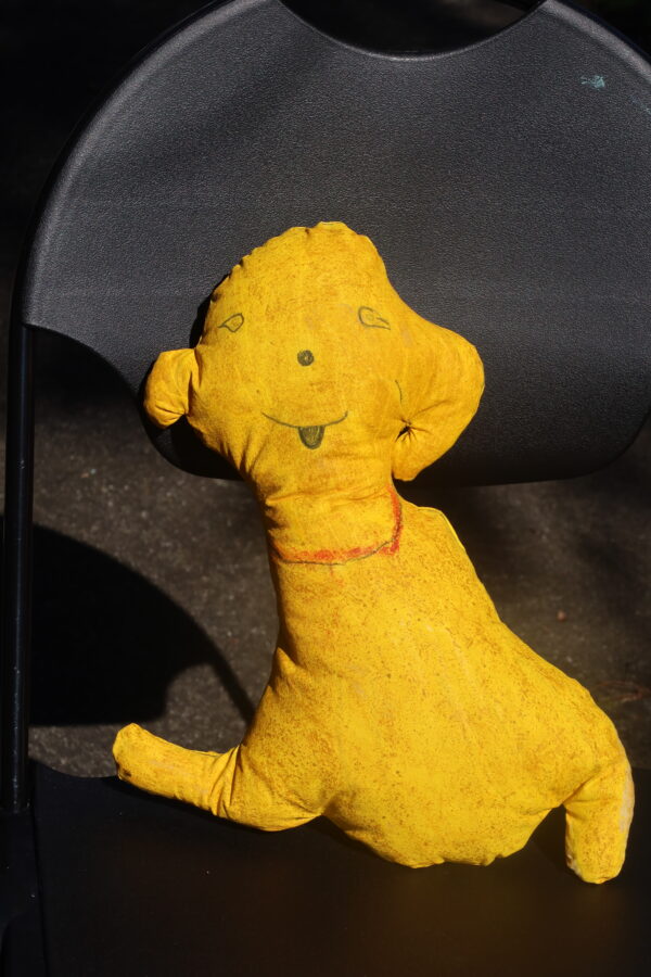 A soft sculpture of an animalistic friendly yellow dog.