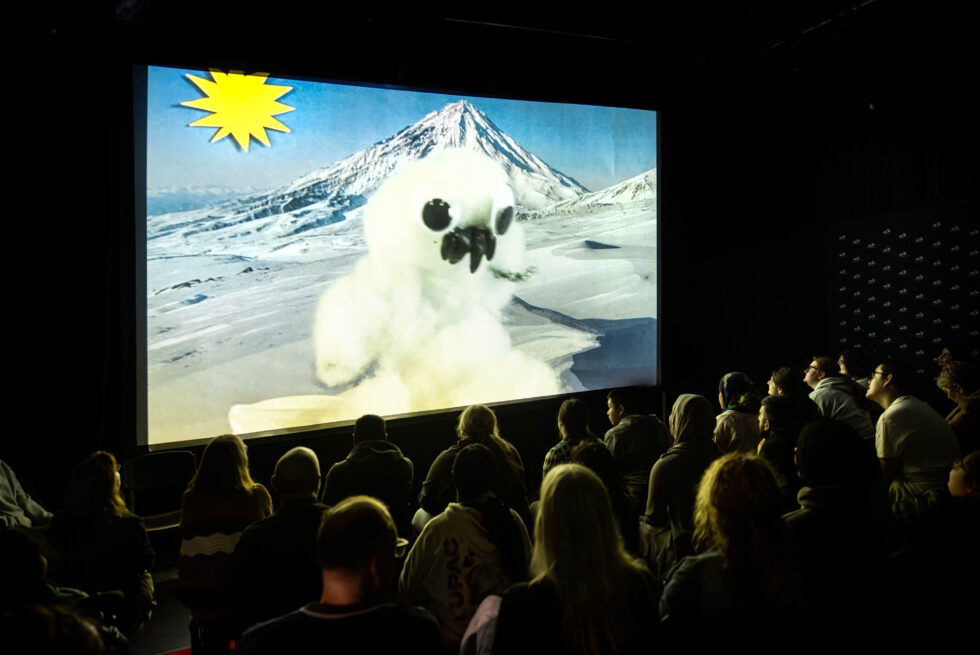 People seated in a cinema watching a film with puppets.