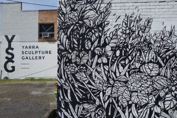 A photo outside the Yarra Sculpture Gallery. There is a beautiful mural by Manda Lane on a brick wall with black and white floral and plant illustration