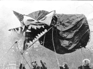 a monster is held up in the air by large polls.