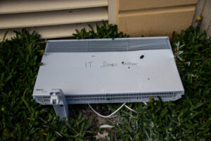 a portable heater missing a leg with “it doss work” written on it in permanent marker