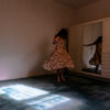self portrait (me) - a woman in a long floral dress twirling around in an unfurnished room
