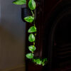 a leafy green plant in a black pot hanging from a red fireplace catching the sunlight