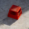 a bright orange portable step stool creating a shadow in the afternoon light