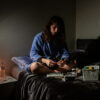self portrait (me) - a woman sitting on a bed in a dressing gown preparing medications