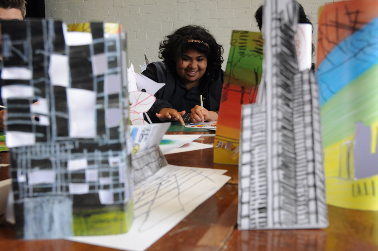 A person looking between paper models of buildings and skyscrapers.