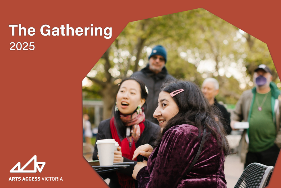 2 people sit at a table with others gathered behind.