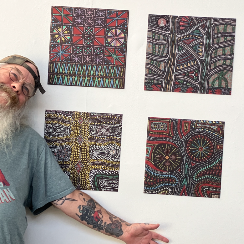 A person with arm stretched out in front of their artwork proudly.